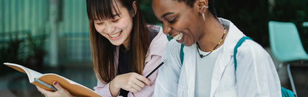 Multiracial female students with workbooks talking outside